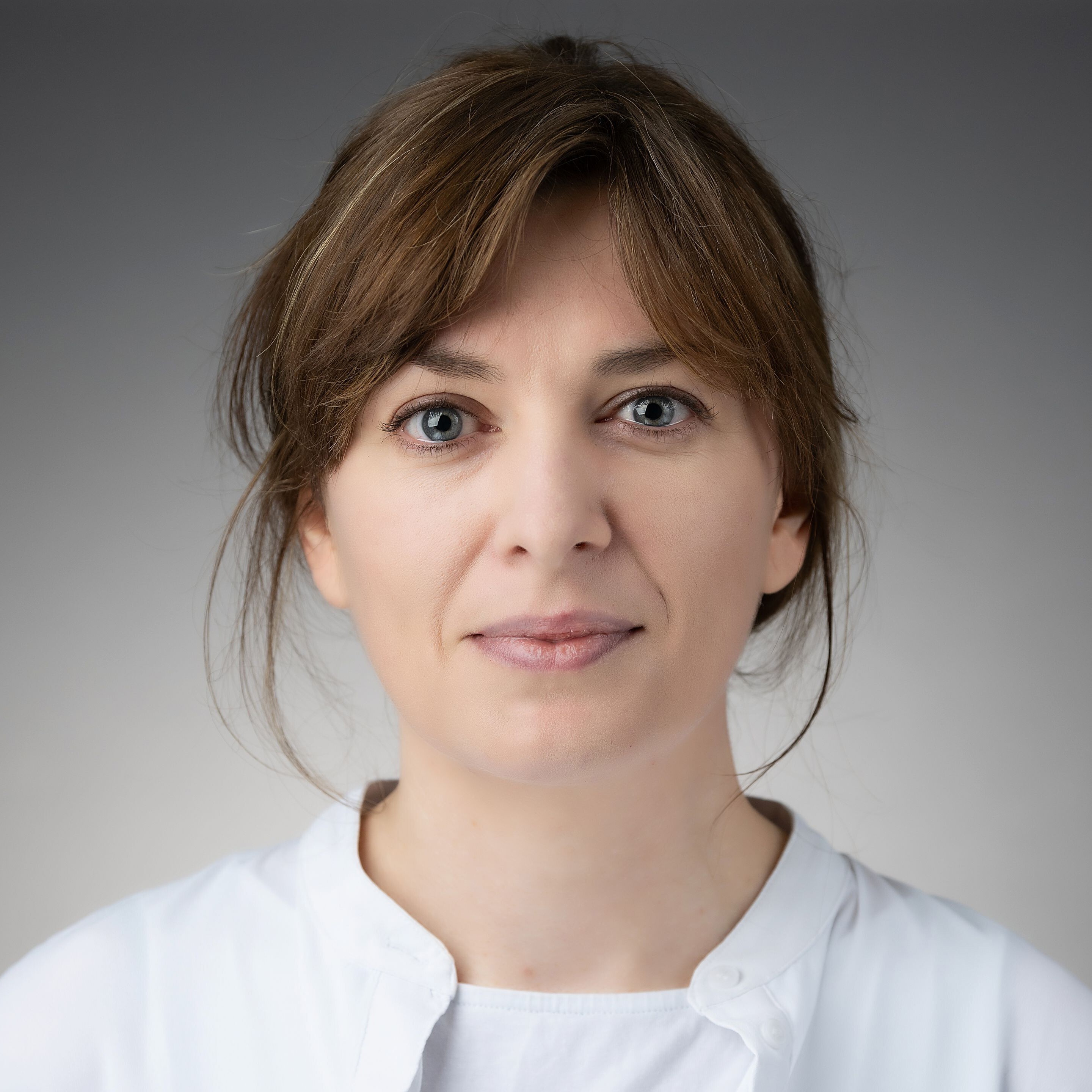 Headshot of Rachel McMahon. Rachel has a fringe and wears a white top